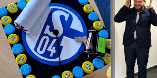 Sebastian Lange mit Doktorhut Links im Bild ist eine Nahaufnahme mit Sicht von oben auf den Doktorhut. Der Hut ist mit einem Schalke-Logo einem funktionstüchtigen Elektrischen-Maschine sowie rings herum gelben und blauen Stauder-Kronkorken verziert. Rechts davon befindet sich ein Bild von Sebastian Lange im Anzug mit aufgesetztem Hut, breitem Grinsen und erhobenen Händen.