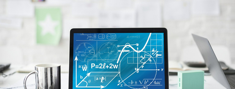 Ein Laptop mit mathematischen Formeln steht auf einem weißen Schreibtisch neben einer Tasse, Stiften und Blättern.